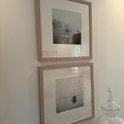 Pair of framed art prints depicting serene water scenes, presented in matching light wood frames with wide matting.