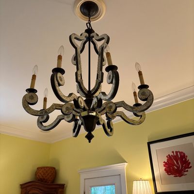 French provincial style eight-light chandelier with an antiqued silver finish, scrolled arms, and decorative leaf motifs.