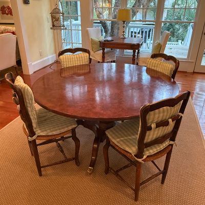 Round mahogany dining table set on a pedestal base with brass feet, accompanied by four French provincial style ladderback chairs with...