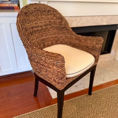 Woven seagrass barrel armchair featuring a dark wood frame and a cream upholstered seat cushion.