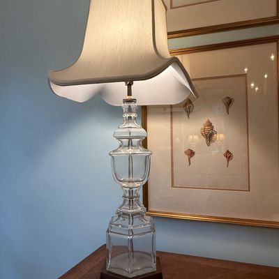 Sale Photo Thumbnail #111: Traditional clear pressed glass table lamp featuring a urn-shaped body on a dark base with an off-white curved pagoda-style lampshade.