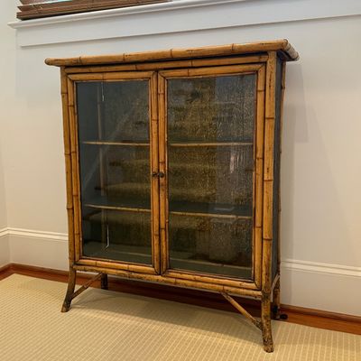 Sale Photo Thumbnail #102: Vintage faux bamboo display cabinet featuring two glass-paneled doors, interior shelving, and a patterned back panel.