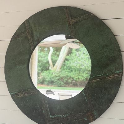 Large round wall mirror featuring a heavily verdigris-patinated copper or metal tiled frame, showing rustic distress and minor silver...