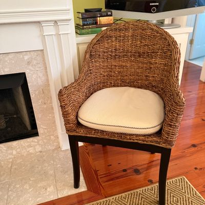 Woven seagrass barrel armchair featuring dark wood legs and a cream-colored seat cushion.