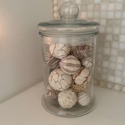 Clear glass apothecary jar filled with decorative neutral-toned spheres, suitable for table or counter accenting.