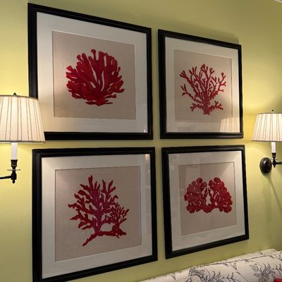 Set of four framed red coral botanical prints mounted on linen-style matting with thick black wood frames.