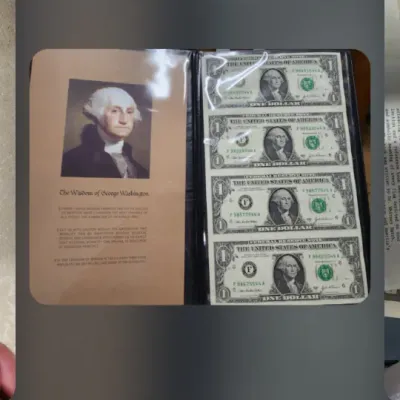 A screenshot of a mobile phone displaying a photo of a George Washington commemorative currency album containing four uncirculated...
