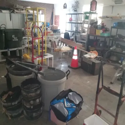 Assorted garage items including hand trucks, plastic trash cans, shelving units, and various tools.
