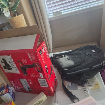 Sale Photo Thumbnail #84: Craftsman V20 cordless drill in its original red box, shown alongside a black and grey sling backpack on a table.
