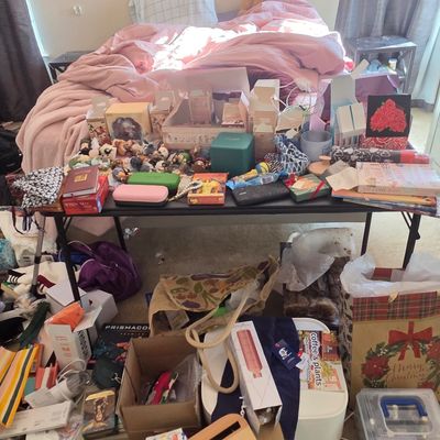 Sale Photo Thumbnail #60: Assorted collection of household items, including books, gift bags, small figurines, and storage boxes, displayed on and around a folding table.