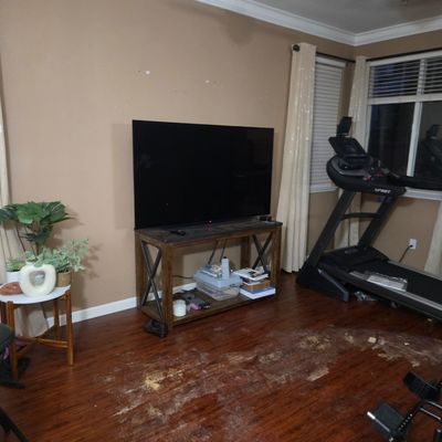 Sale Photo Thumbnail #18: Large flat-screen television on a rustic wood and metal console table, alongside a Spirit treadmill in a home gym or living area.