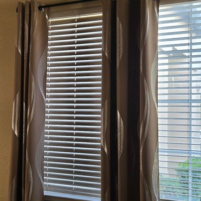 Sale Photo Thumbnail #37: Pair of brown grommet-top curtain panels featuring a modern wavy silver line pattern, shown hanging on a black rod over window blinds.