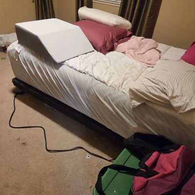 Sale Photo Thumbnail #31: Adjustable bed frame with mattress, bedding, and a foam wedge pillow.