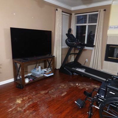 Sale Photo Thumbnail #16: Spirit motorized treadmill, a flat-screen television on a rustic wood and metal media console, and a Drive medical wheelchair in a living room setting.