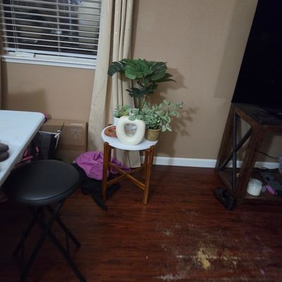 Sale Photo Thumbnail #19: Small round accent table with a white top and wooden legs, holding a modern white ceramic donut vase and artificial potted plants.