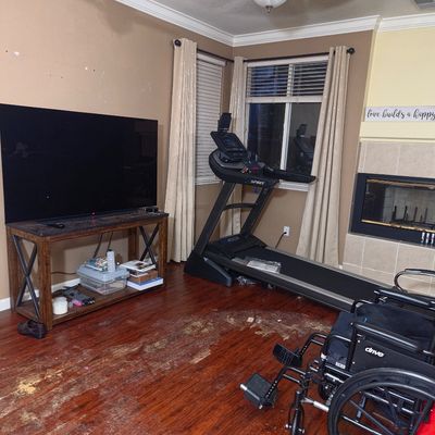 Sale Photo Thumbnail #17: Spirit motorized treadmill, a Drive medical wheelchair, and a large flat-screen television on a rustic wooden stand.