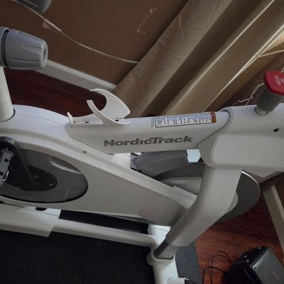 Sale Photo Thumbnail #13: NordicTrack stationary exercise bike in white, featuring a water bottle holder and a red emergency stop button.