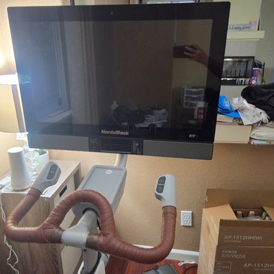 Sale Photo Thumbnail #7: NordicTrack stationary exercise bike featuring a large integrated touchscreen display and brown textured handlebar grips.