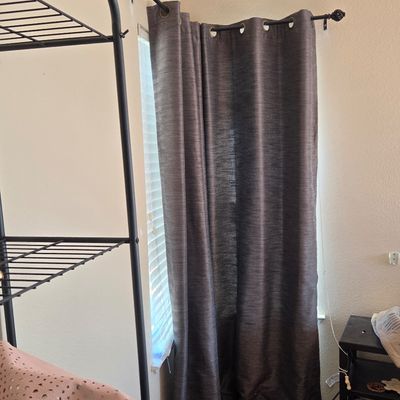 Sale Photo Thumbnail #64: Dark grey grommet-top curtain panel hanging on a black metal curtain rod with decorative finials.