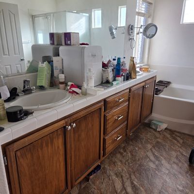 Sale Photo Thumbnail #68: Double-sink bathroom vanity with wood cabinetry, white tile countertop, and a large wall-mounted mirror.
