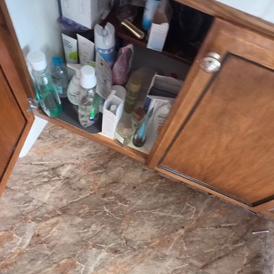 Sale Photo Thumbnail #58: Assorted personal care products, toiletries, and cosmetics stored inside a wooden bathroom vanity cabinet.