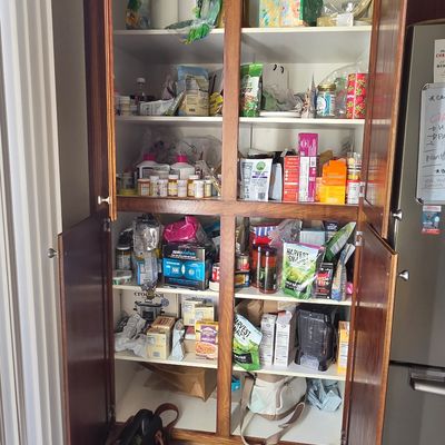Sale Photo Thumbnail #39: Built-in wooden kitchen pantry cabinet with double doors, filled with various dry goods, snacks, and household items.
