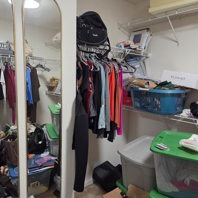Sale Photo Thumbnail #30: Assorted clothing on hangers, storage bins, and miscellaneous closet items, alongside a gold-framed arched mirror.
