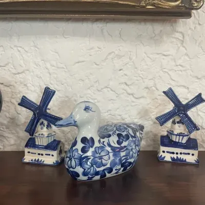 Delft-style blue and white glazed ceramic duck figurine flanked by two matching miniature windmill salt and pepper shakers.