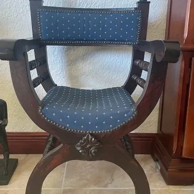 Renaissance Revival style Savonarola or curule armchair featuring dark-stained carved wood frame and blue patterned upholstery with...