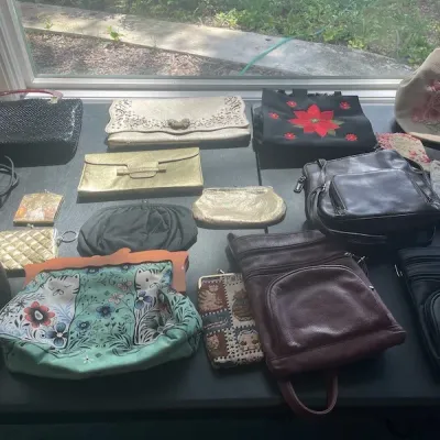 Assortment of vintage and modern handbags, clutches, and coin purses, featuring metallic evening bags, leather crossbodies, and novelty...