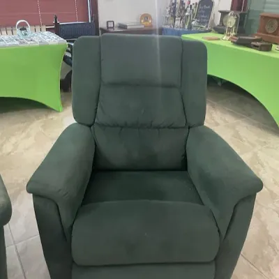 Dark green plush upholstered recliner with a segmented high back and padded armrests.