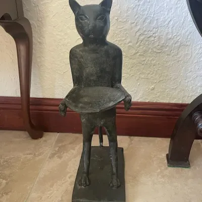 Cast dark metal cat butler statue holding a tray, set on a rectangular base with an aged dark patina.