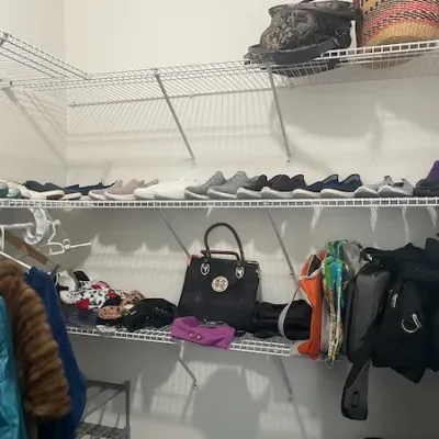 Walk-in closet shelving lined with various women's shoes, handbags, athletic bags, and clothing.