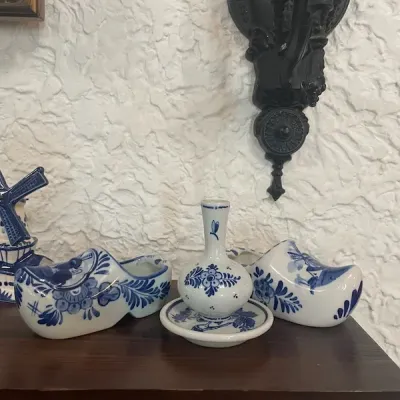 Collection of blue and white Delfts-style ceramic decor, including miniature clog shoes, a small bud vase with saucer, and a windmill...
