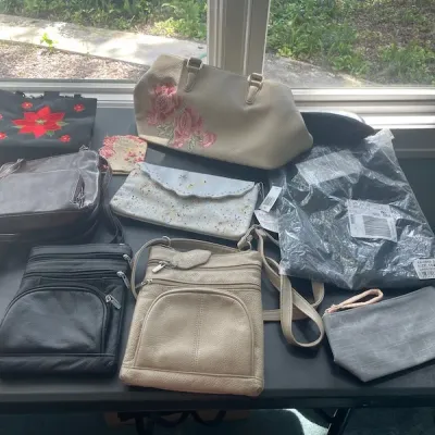 Collection of assorted women's handbags, crossbody purses, and clutches arranged on a table.