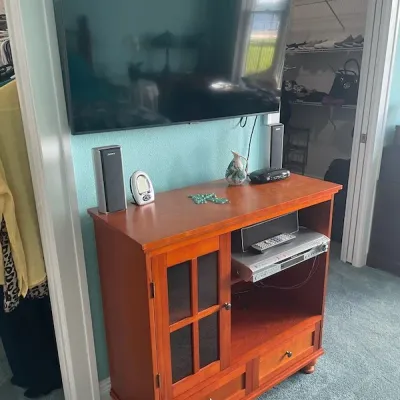 Warm cherry wood media console cabinet with a glass-pane door, lower drawers, and open shelving housing electronics.