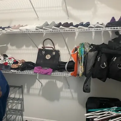 Walk-in closet featuring wire shelving lined with women's athletic shoes, leather and nylon handbags, outerwear, and accessories.