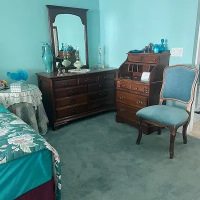 Vintage dark wood bedroom suite featuring a multi-drawer dresser with attached arched mirror, a slant-top secretary desk, and a matching...