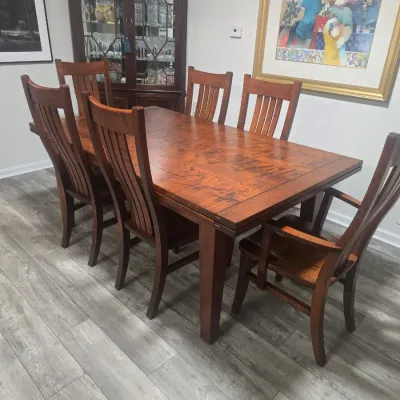 Mission-style wooden dining table with six matching slat-back chairs, featuring a rich reddish-brown finish.