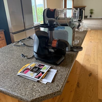 Sale Photo Thumbnail #14: Ninja Cold Press Juicer Pro in black, shown with its user manual on a kitchen island alongside another small appliance.