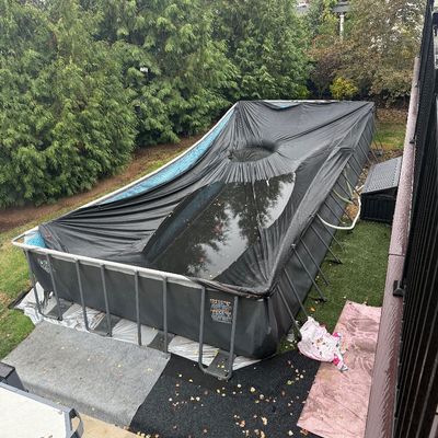 Sale Photo Thumbnail #12: Large rectangular above-ground swimming pool with a metal support frame and a black winter cover collecting rainwater.