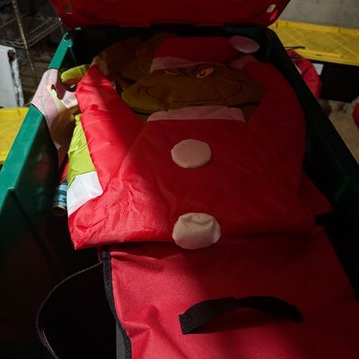 Sale Photo Thumbnail #50: Inflatable Grinch Christmas decoration folded inside a green and red plastic storage bin.