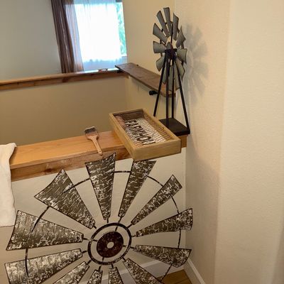 Sale Photo Thumbnail #29: Rustic farmhouse decor items, including a large distressed metal windmill wall hanging, a smaller tabletop windmill sculpture, and a wooden tray with wire mesh.