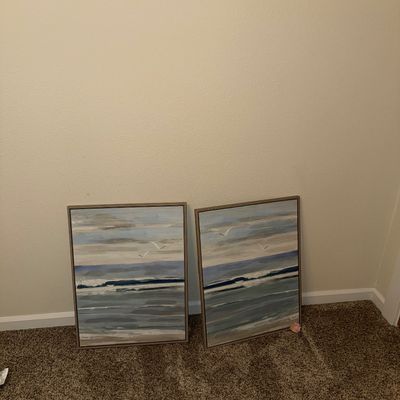 Sale Photo Thumbnail #34: Pair of contemporary framed canvas prints depicting abstract coastal ocean scenes with seagulls, in muted blue, grey, and beige tones.