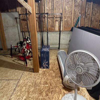 Sale Photo Thumbnail #19: Lasko white pedestal fan, a rolled-up mattress, a boxed Harbor Breeze ceiling fan, and a Radio Flyer spring rocking horse in an unfinished basement.