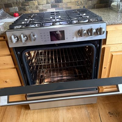 Sale Photo Thumbnail #5: Modern GE Café stainless steel slide-in gas range with a six-burner cooktop and an open oven door showing the interior racks.
