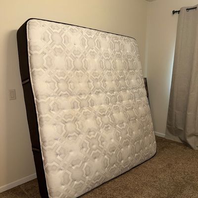 Sale Photo Thumbnail #32: Modern queen-size mattress with a white and grey geometric patterned top and dark fabric sides, shown propped against a wall.