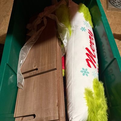 Sale Photo Thumbnail #49: Assorted Christmas decorations, including a long "Merry" pillow with green faux fur trim and collapsible wooden display pieces, stored inside a green plastic bin.