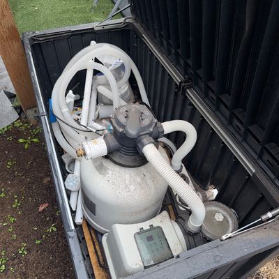 Sale Photo Thumbnail #10: Intex above-ground pool sand filter pump system with hoses and accessories, stored inside a black plastic deck box.
