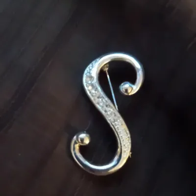 Silver-tone S-shaped initial brooch accented with pave-set clear rhinestones and ball terminal ends.